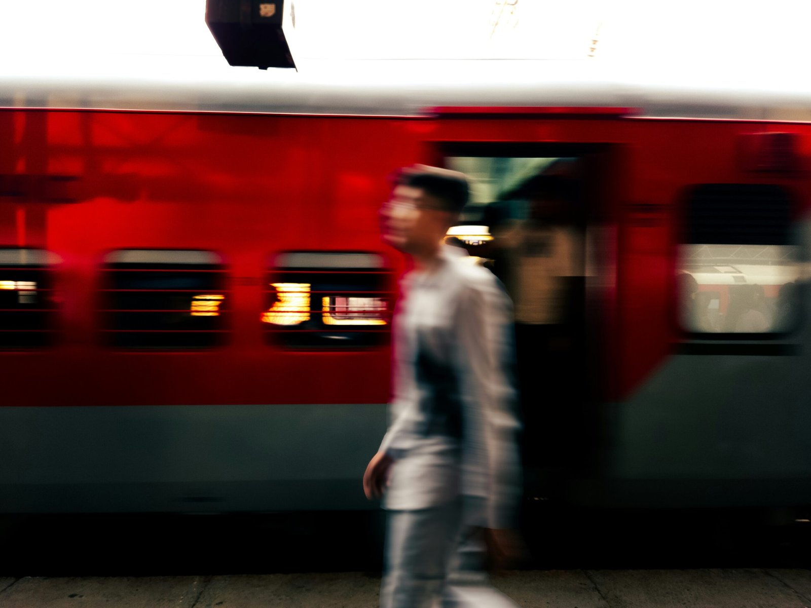 A blurry photo of a man walking in front of a train