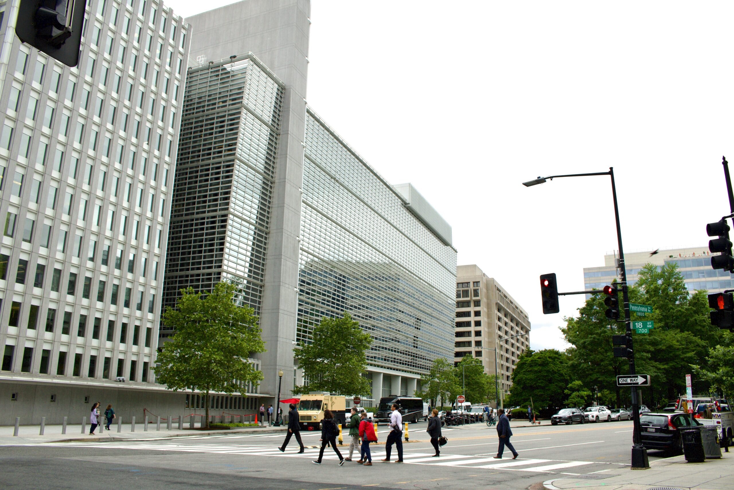 A group of people walking across a street next to tall buildings