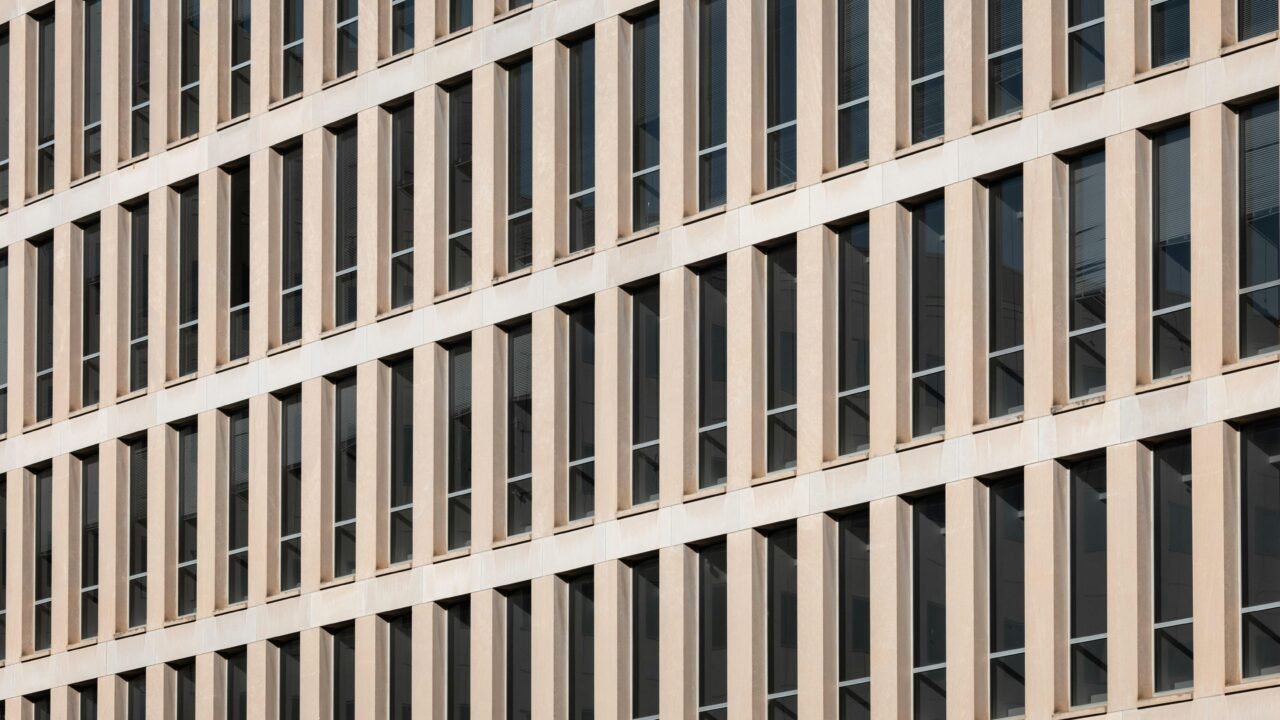 A tall building with lots of windows next to a street sign