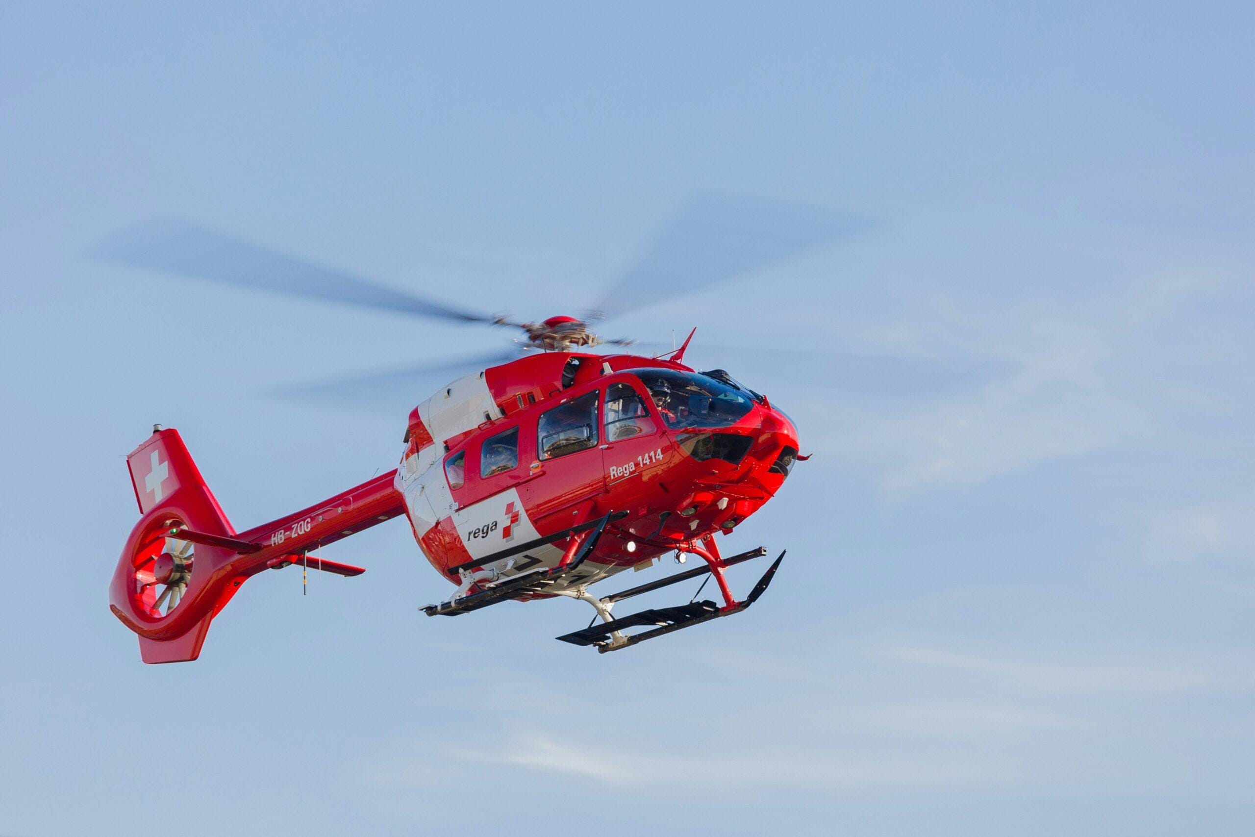 a red and white helicopter flying through a blue sky