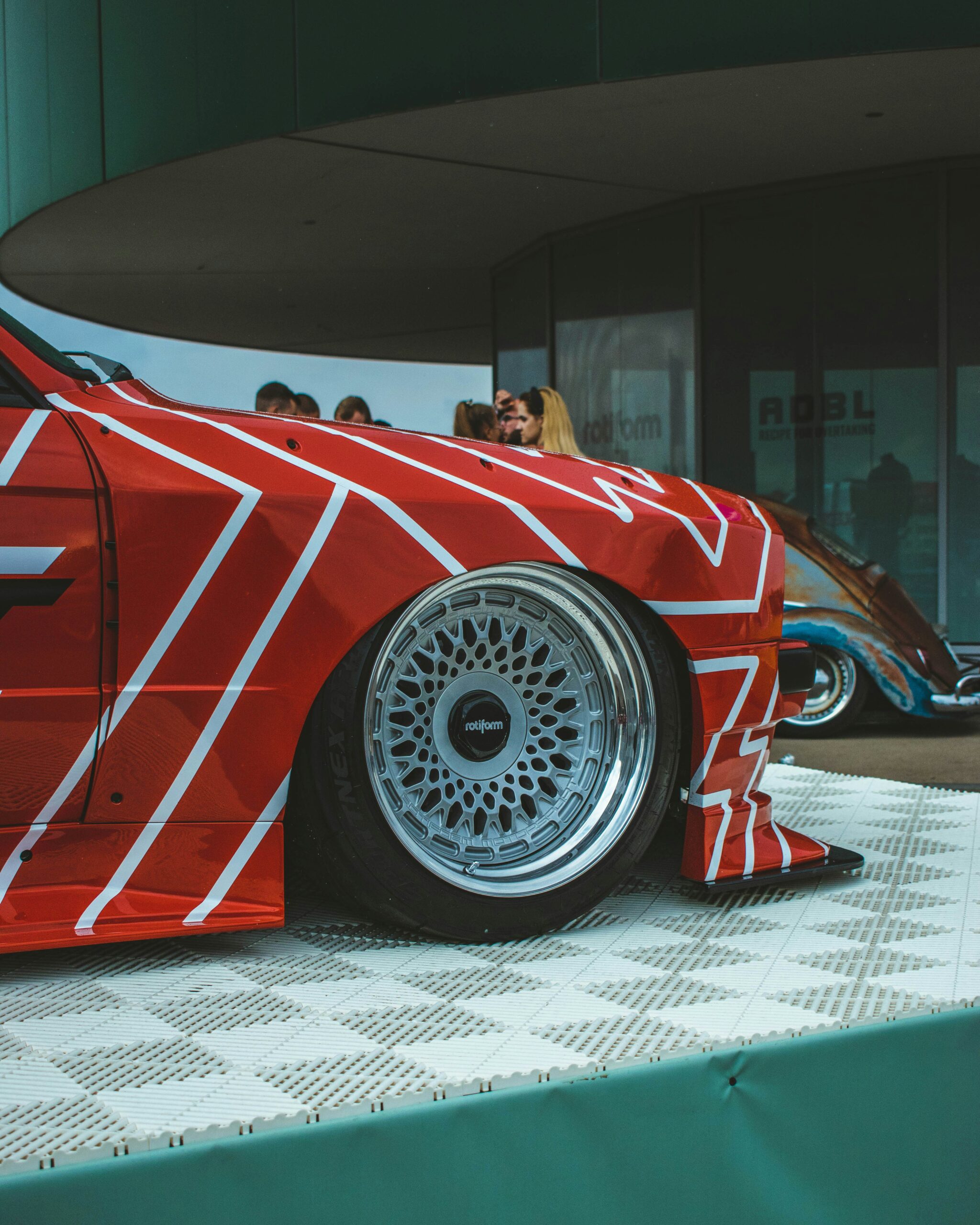 a red car with white stripes parked in front of a building