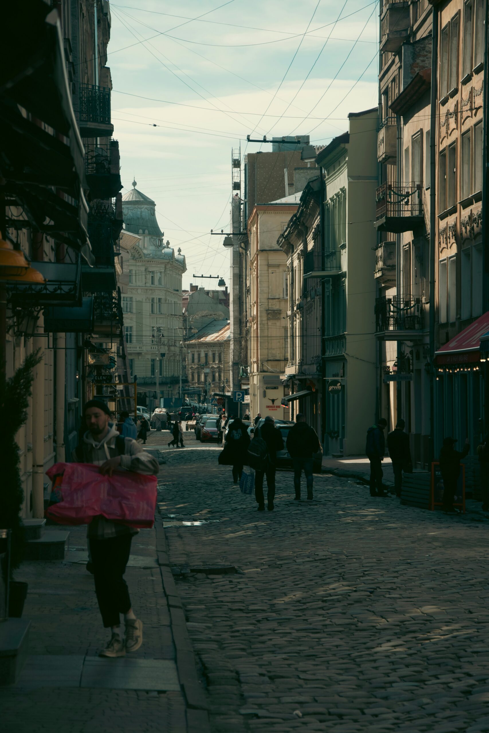 a woman walking down a street holding a pink umbrella