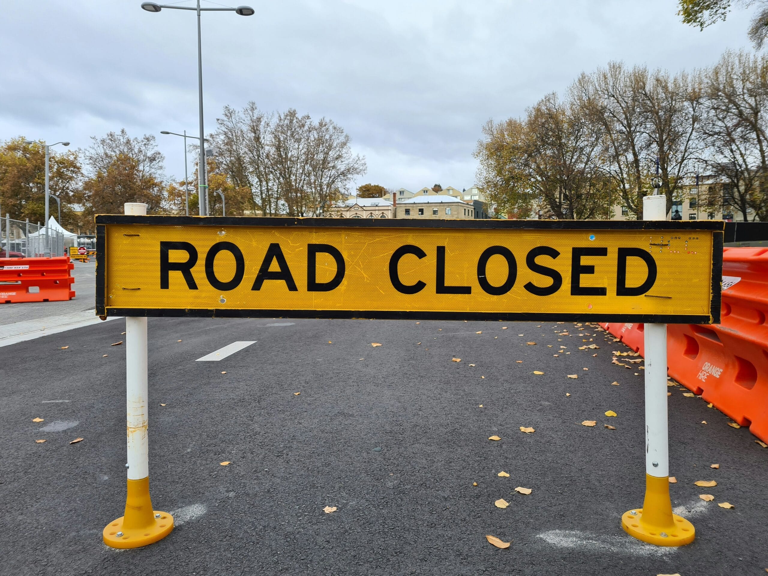 a yellow road closed sign sitting on the side of a road