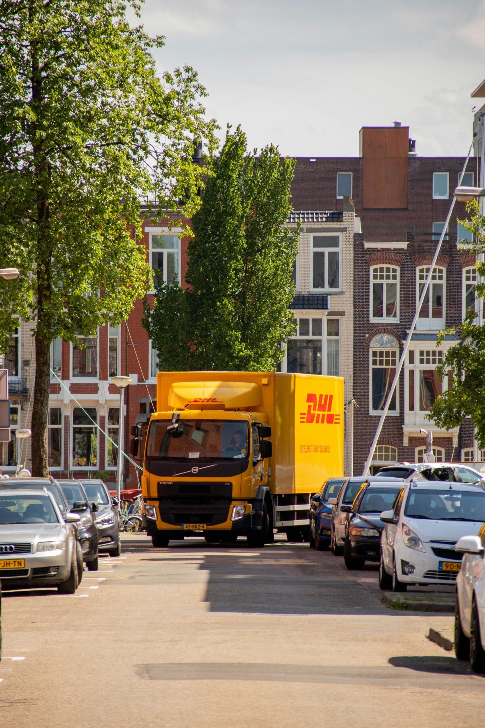 a yellow truck driving down a street next to tall buildings