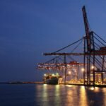 silhouette of crane near body of water during night time