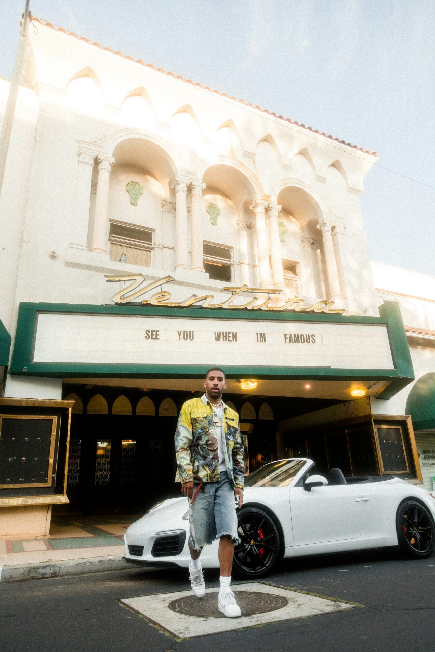 man in gray jacket standing beside white car during daytime