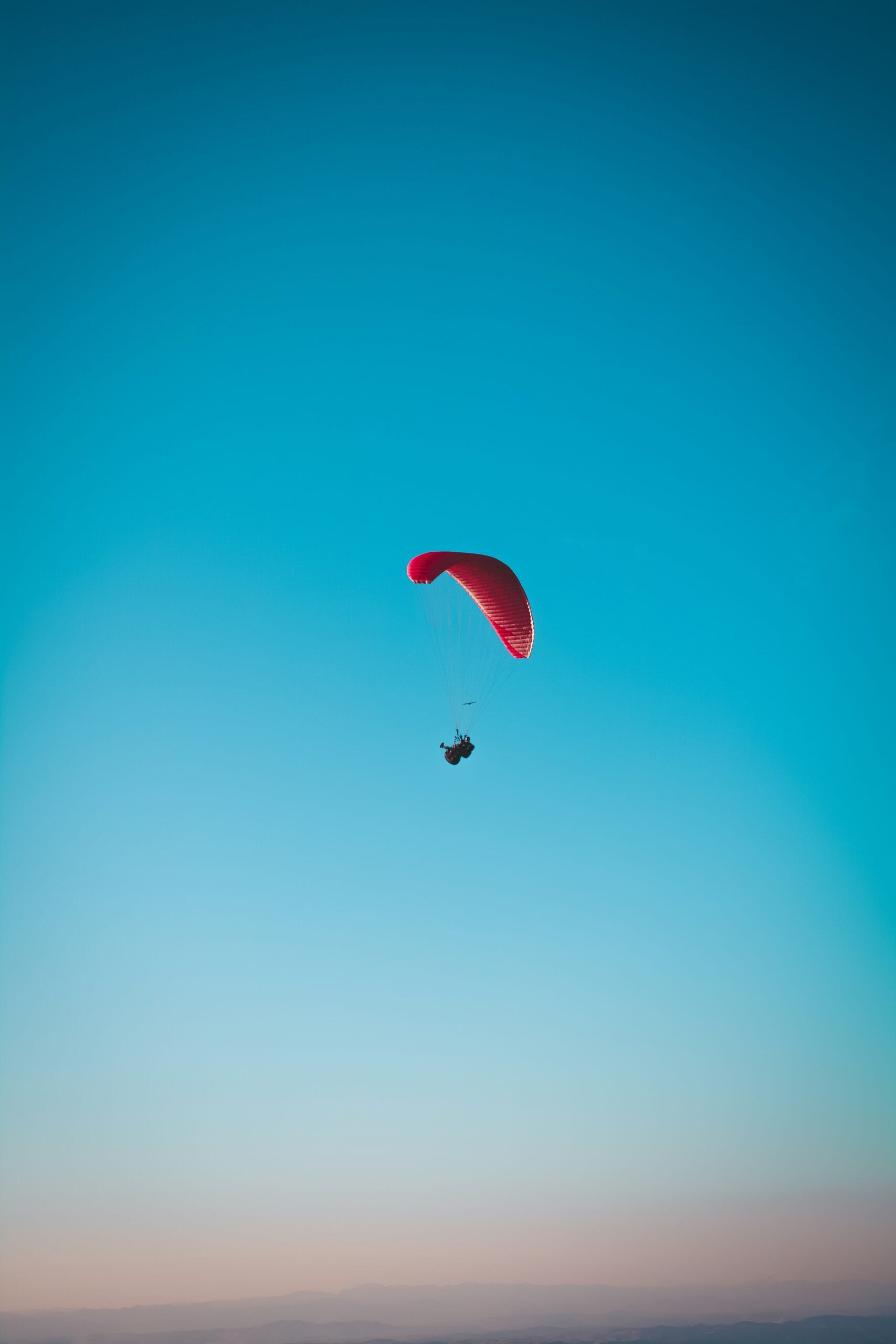 person in red parachute in mid air