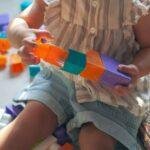 girl in brown button up shirt holding blue and orange plastic toy