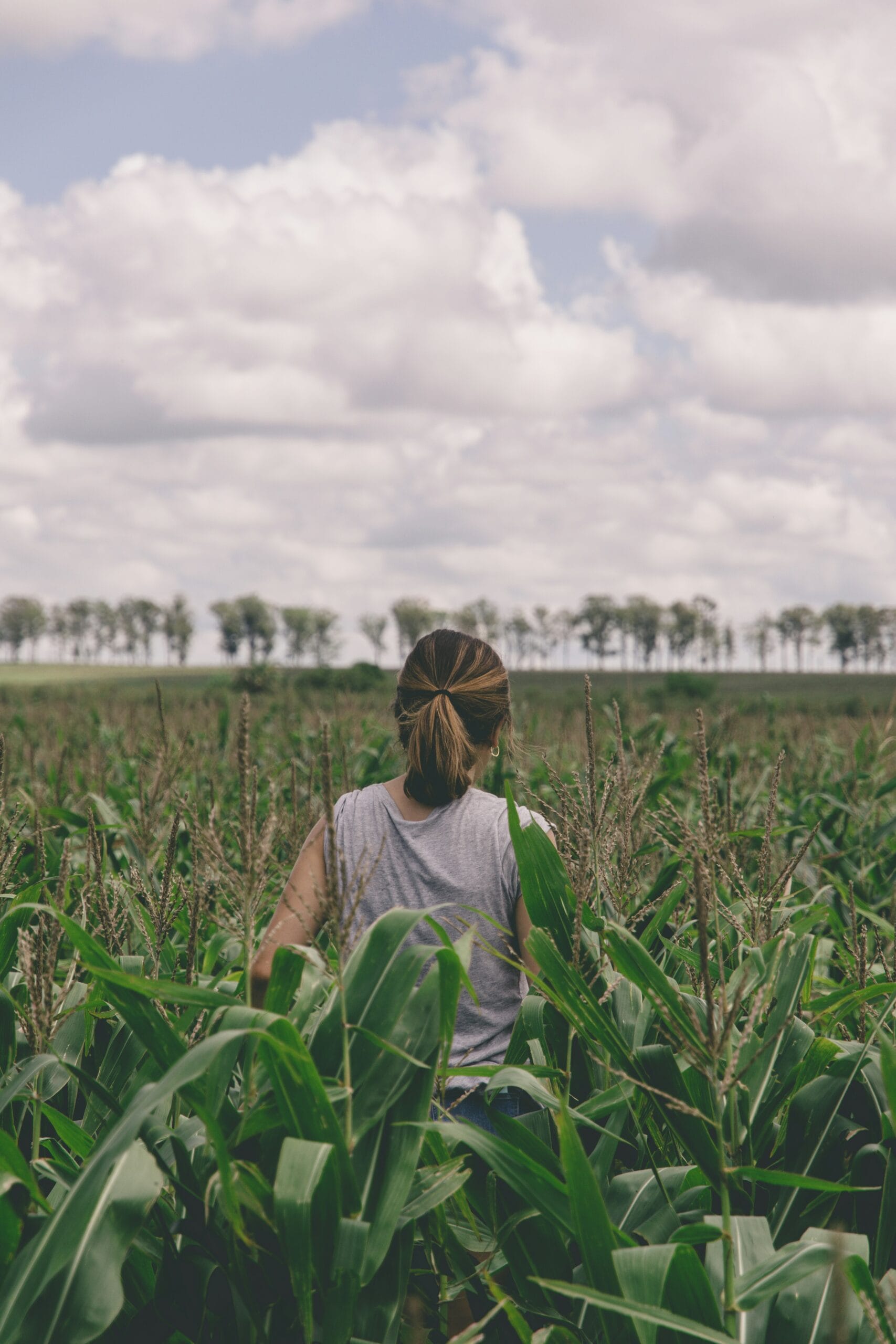 woman in gray shirt standing on green grass field during daytime