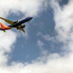 An airplane flying through a cloudy blue sky