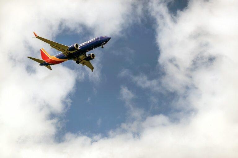 An airplane flying through a cloudy blue sky